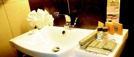 A hotel bathroom with a white sink, a towel, and toiletries on the counter.