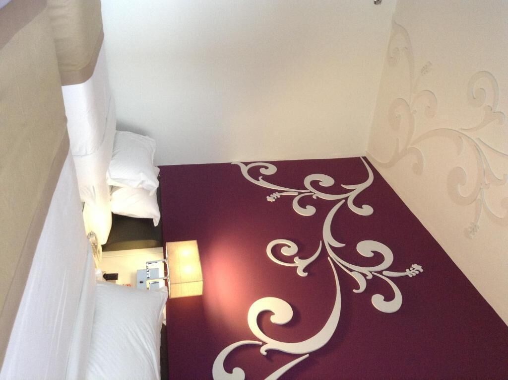 Ein Hotelzimmer mit Bett, Nachttisch, Lampe und einer dekorativen Wandgestaltung.