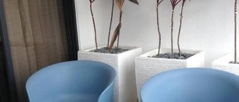 A room with a blue chair, a white table, and a plant.
