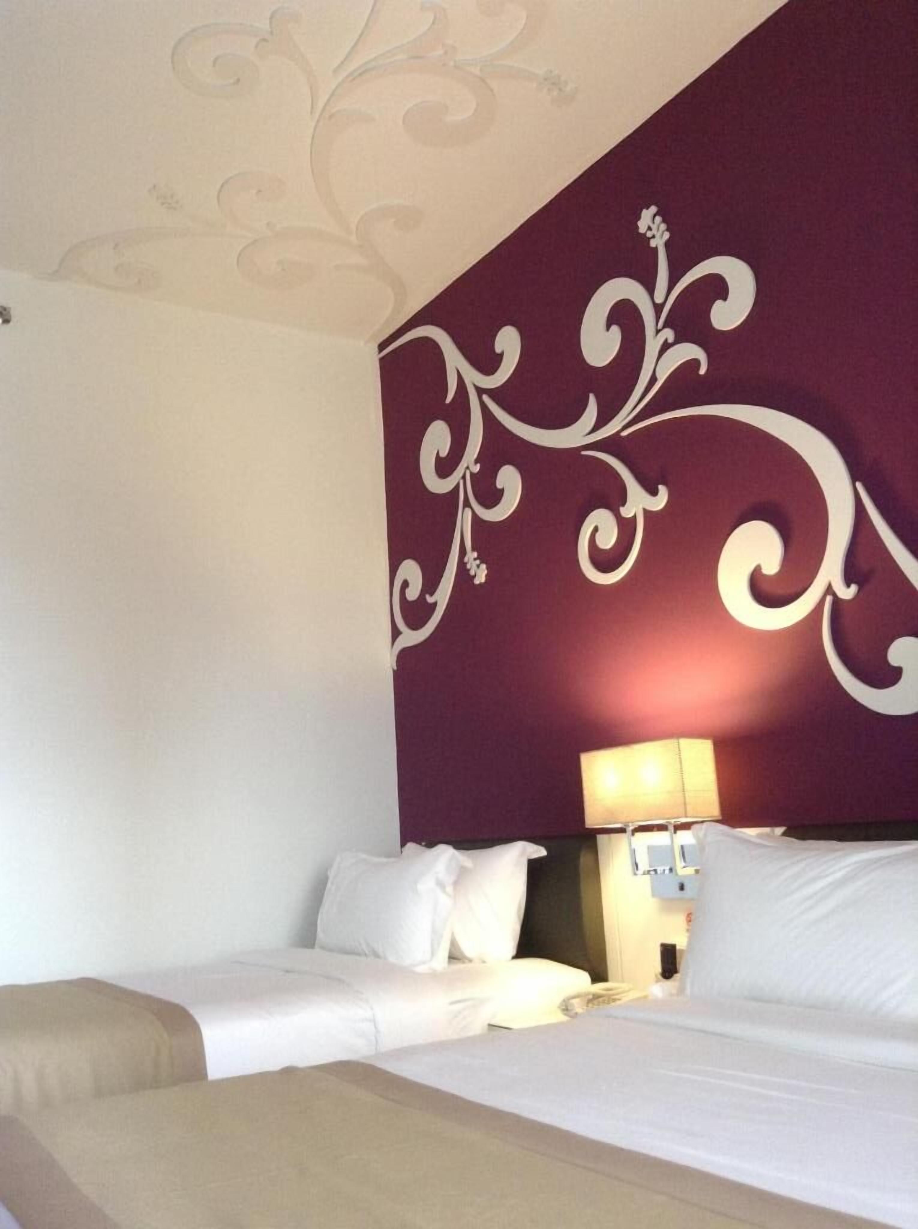 A hotel room with a bed, a nightstand, and a lamp.