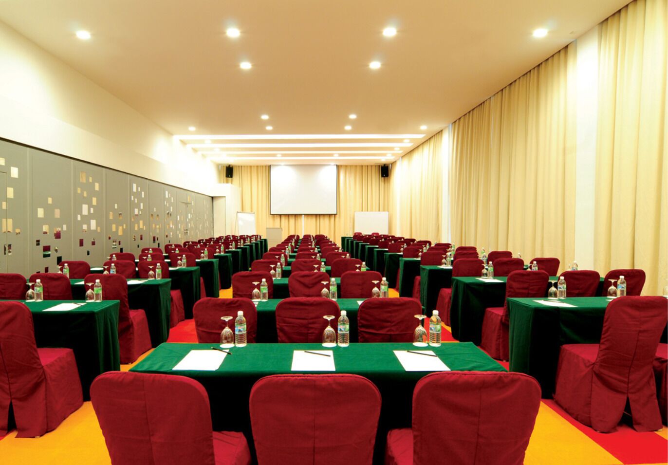 A conference room with rows of tables and chairs, equipped with water bottles and nameplates.