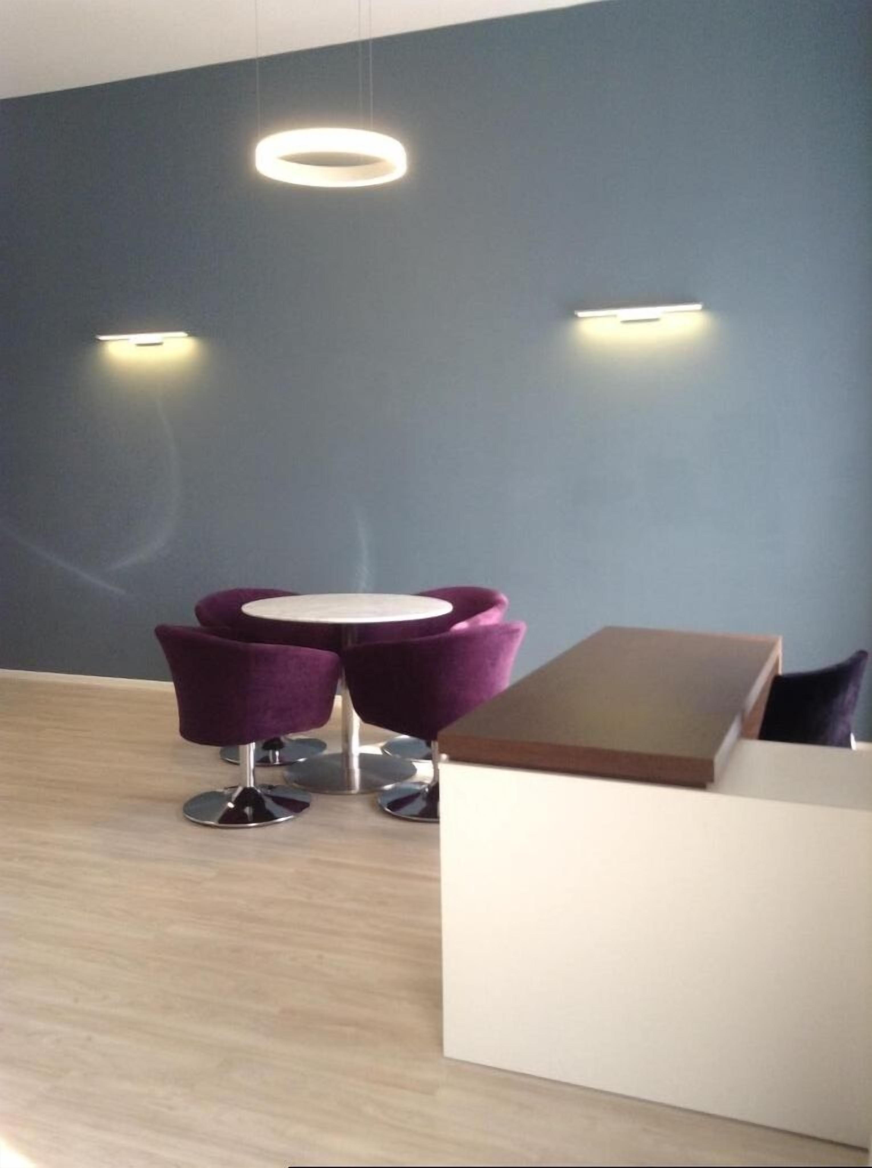 Una habitación moderna con piso de madera, un mostrador de recepción blanco y una silla morada.