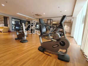 Un gimnasio con máquinas de cardio, equipo de levantamiento de pesas y un muro de espejos.