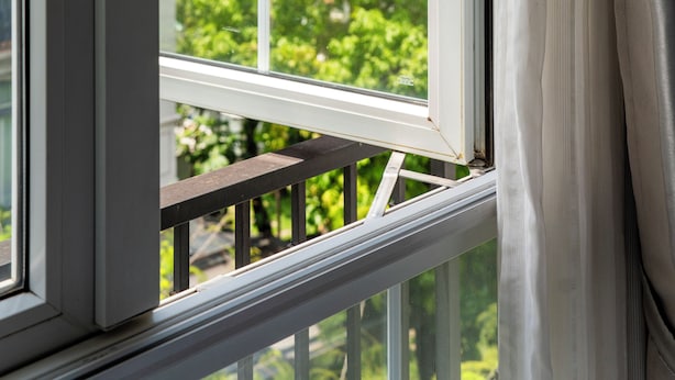 Une fenêtre donnant sur un bâtiment et sur la verdure environnante.