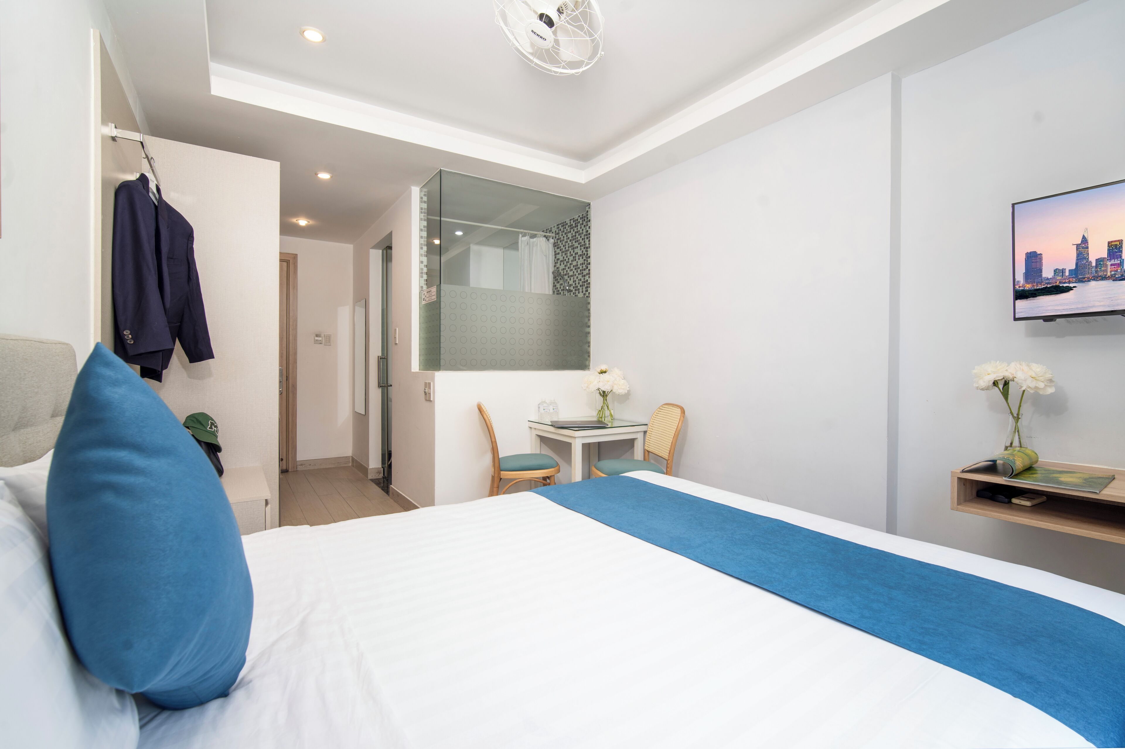 Ein Hotelzimmer mit Bett, Schreibtisch, Stuhl, Spiegel und Fernseher.