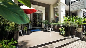 L’entrée d’un hôtel, avec un parasol rouge, des plantes en pot et une enseigne indiquant « Saigon South Serviced Apartments 2 ».
