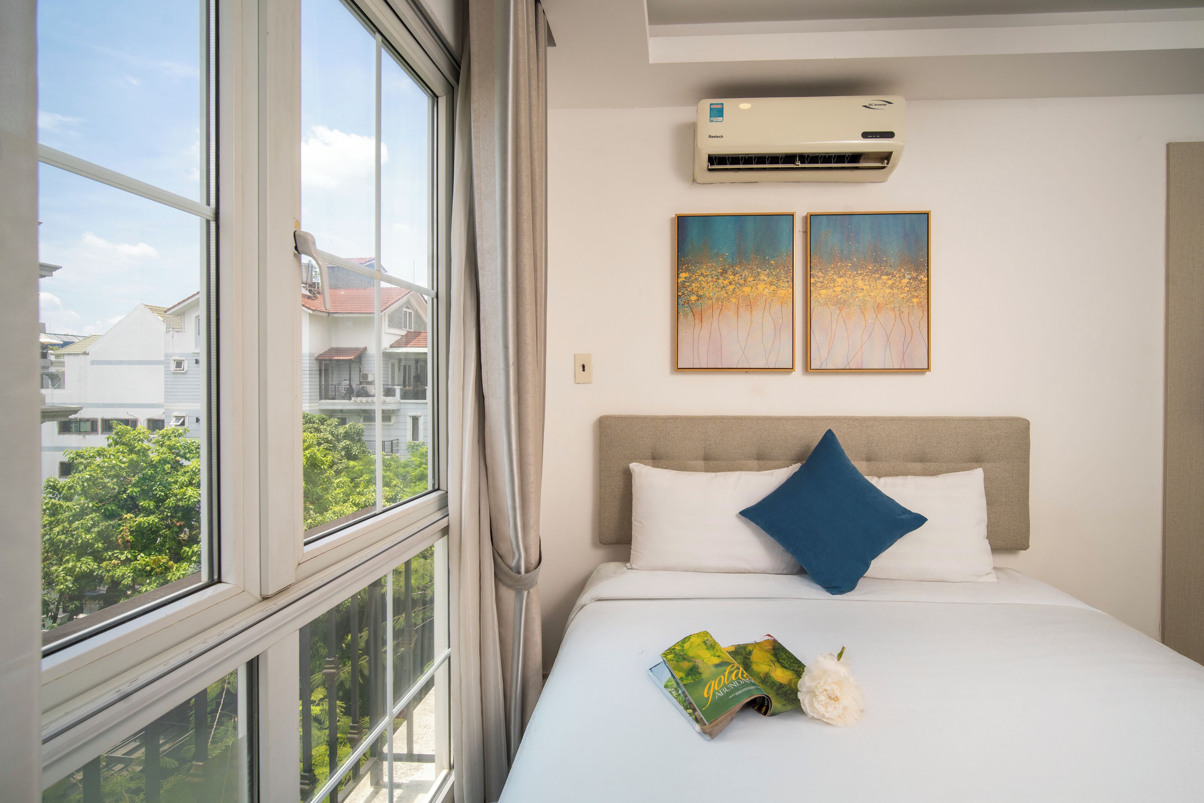 A hotel room with a bed, a window, and an air conditioning unit.