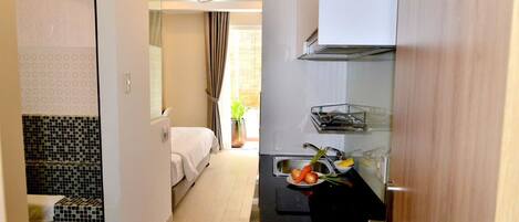 A compact hotel room with a kitchenette, a bed, and a bathroom with patterned tiles.