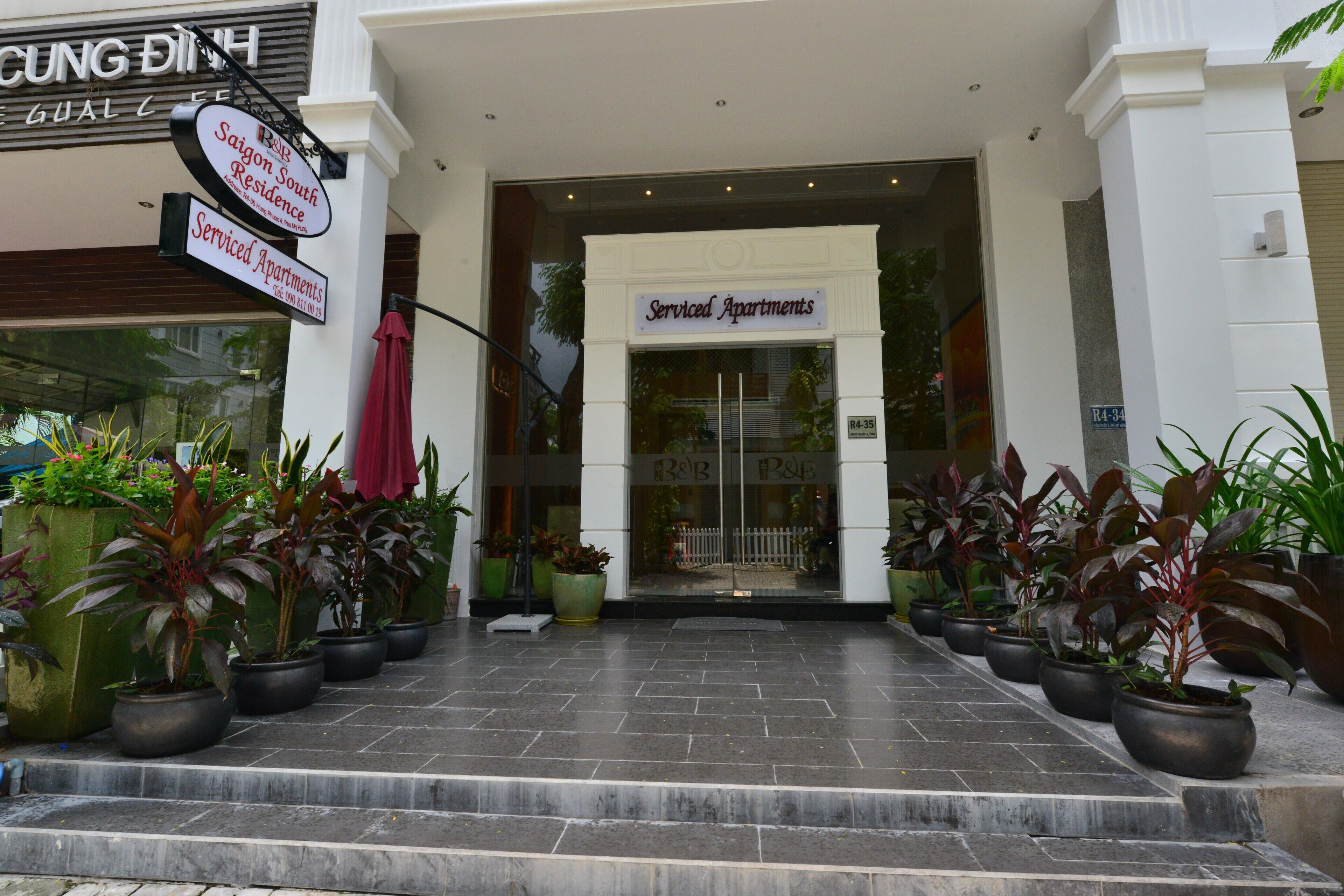 Entrada de um prédio com placa indicando "Serviced Apartments" e placa "Saigon South Residence".