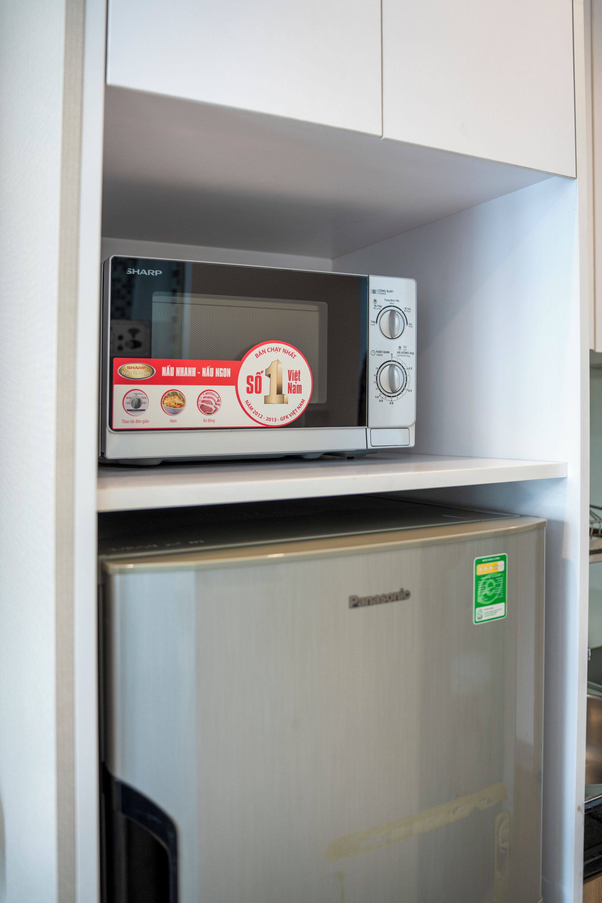 Eine Mikrowelle auf einem Regal über einem Kühlschrank.
