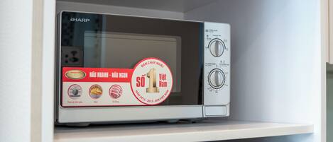 Eine Mikrowelle auf einem Regal über einem Kühlschrank.