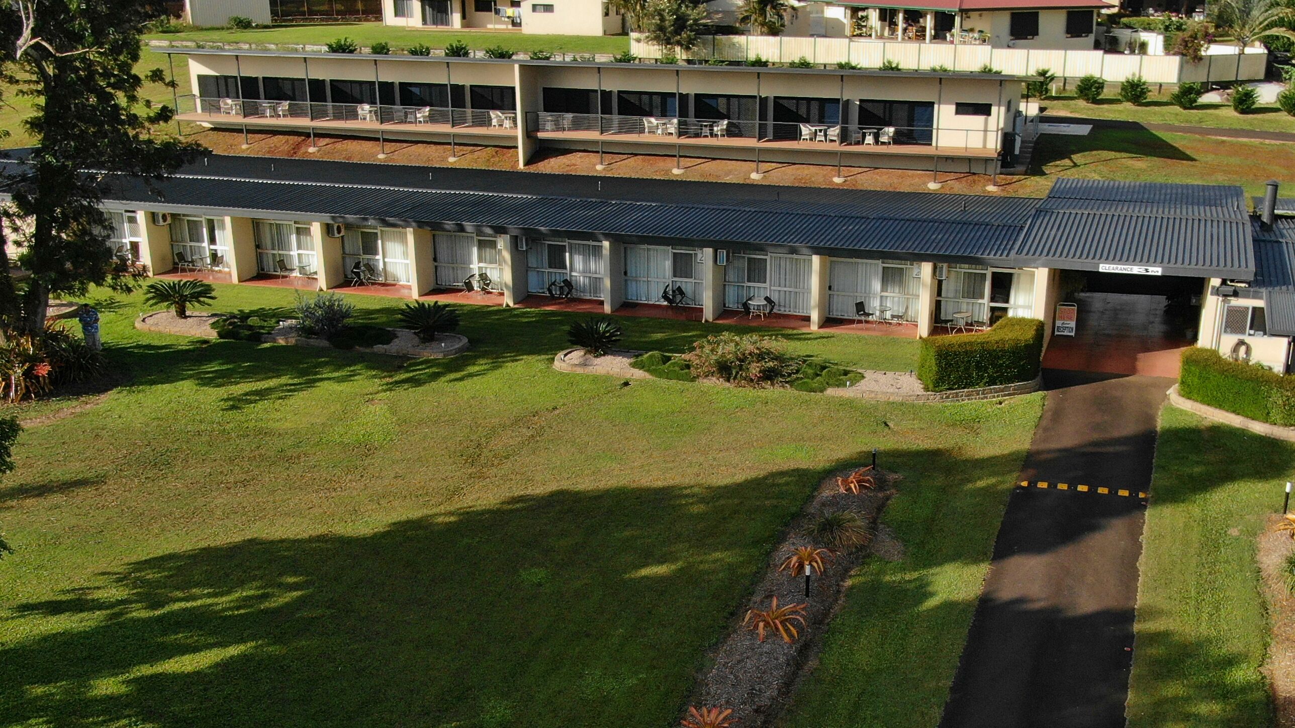 A two-story building with a flat roof, multiple balconies, and a well-maintained lawn.