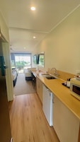 A compact kitchen with a sink, a microwave, and a refrigerator. There is a dining area with chairs and a table, and a balcony with a view.