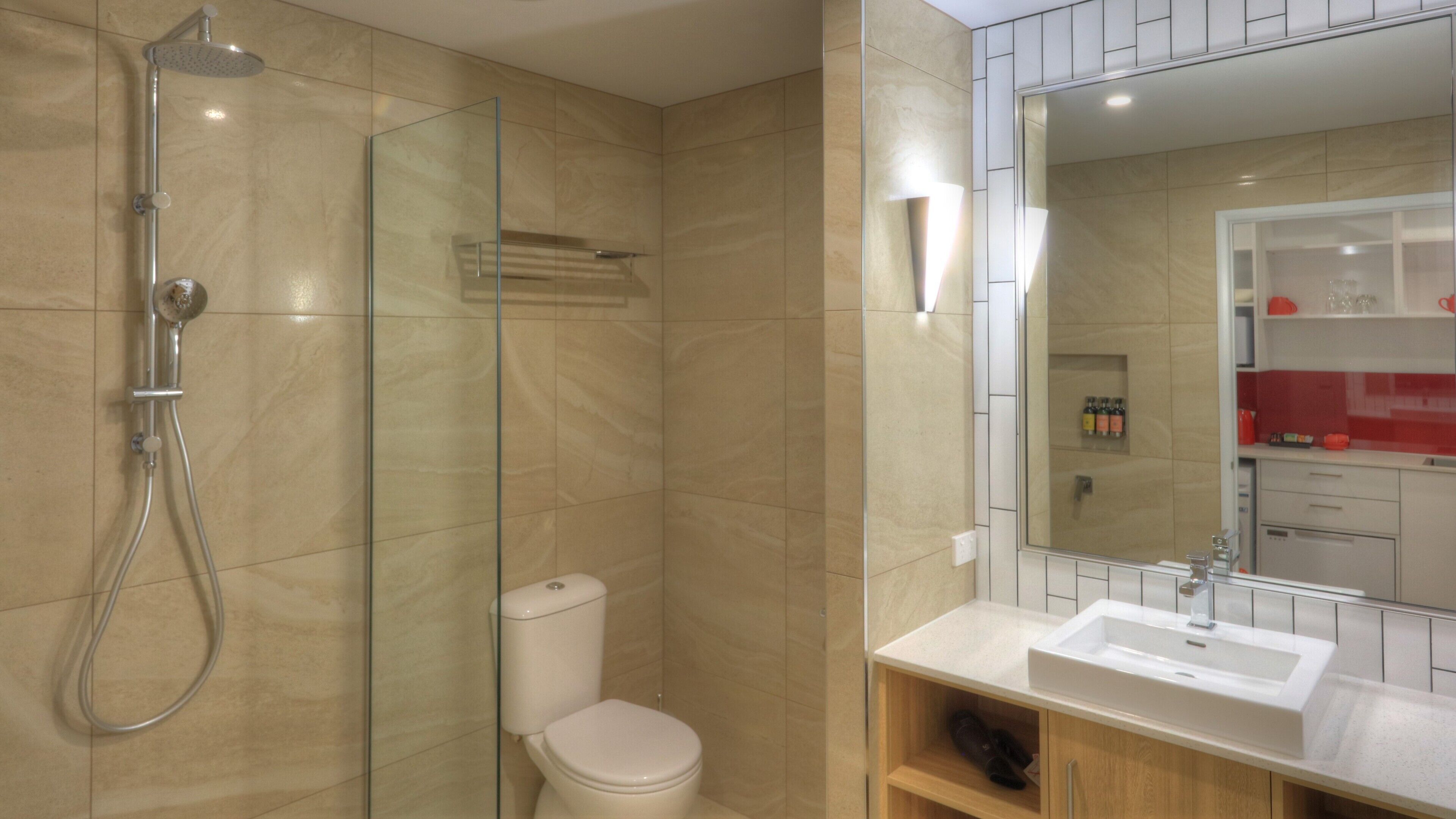 A modern bathroom with a glass-enclosed shower, a toilet, a sink, and a mirror.