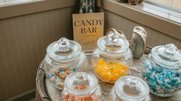 Une enseigne représentant une barre chocolatée et des bocaux remplis de bonbons colorés sont posés sur une table en bois près d’une fenêtre.