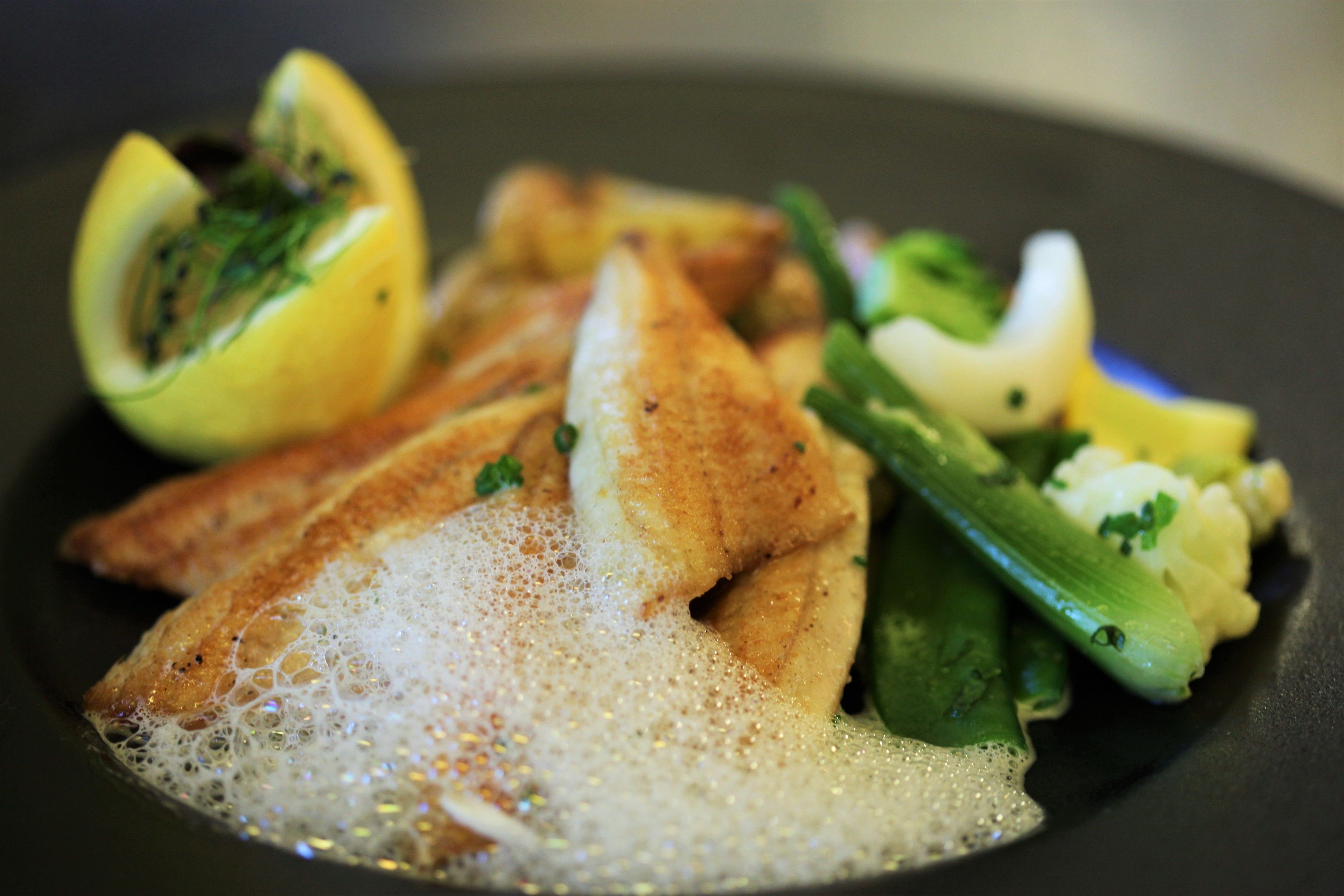 Ein Teller mit Fisch, Zitrone und Gemüse.