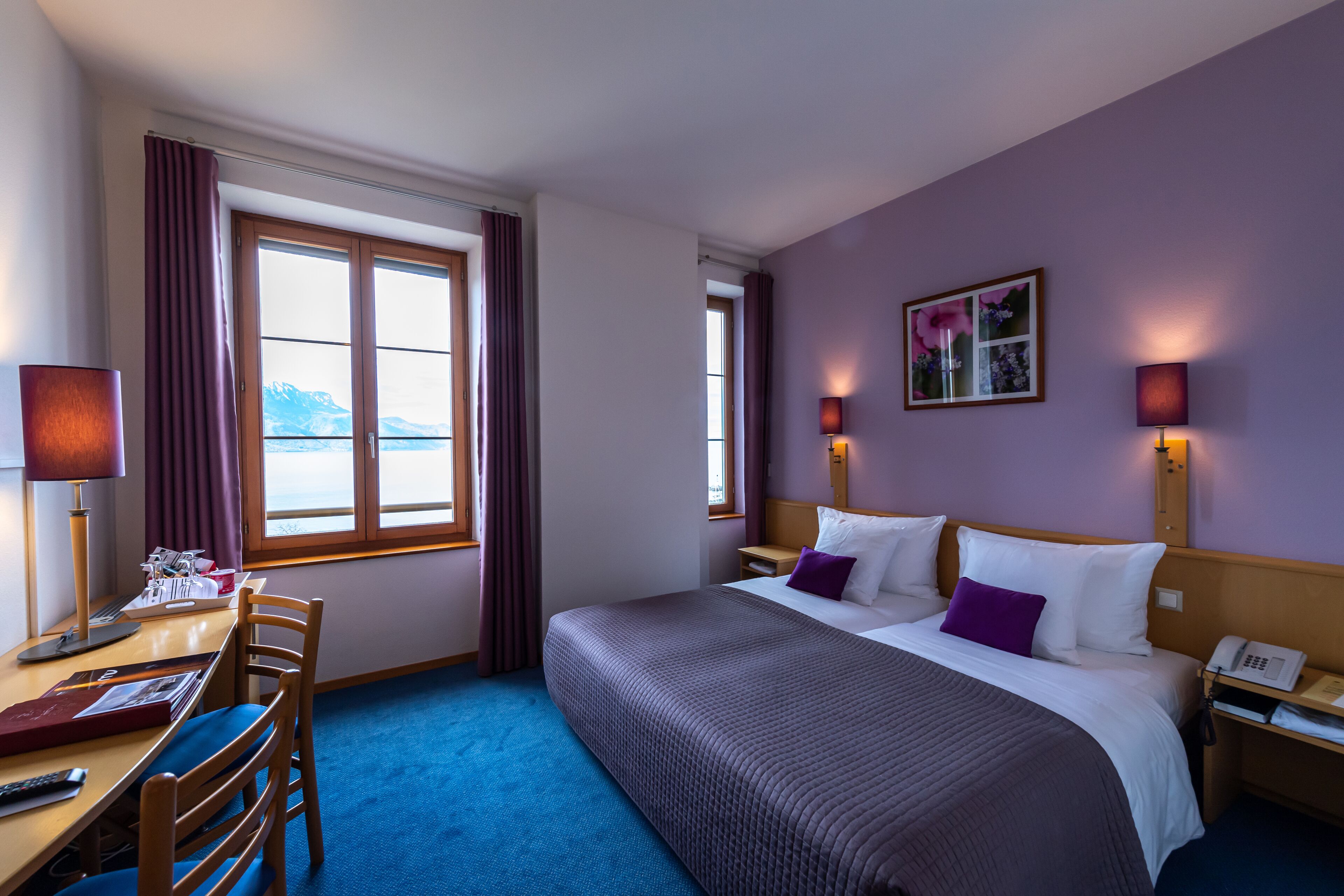 Hotellihuone, jossa on sänky, yöpöydät, työpöytä ja tuoli.
