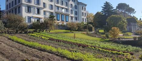 A multi-story building with a garden in front.