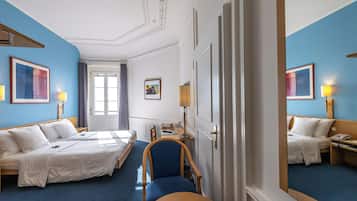 Une chambre d’hôtel avec deux lits, un bureau, une chaise et un miroir.