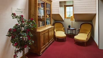 Un rincón acogedor para leer con dos sillones, una estantería de madera y una planta en maceta.