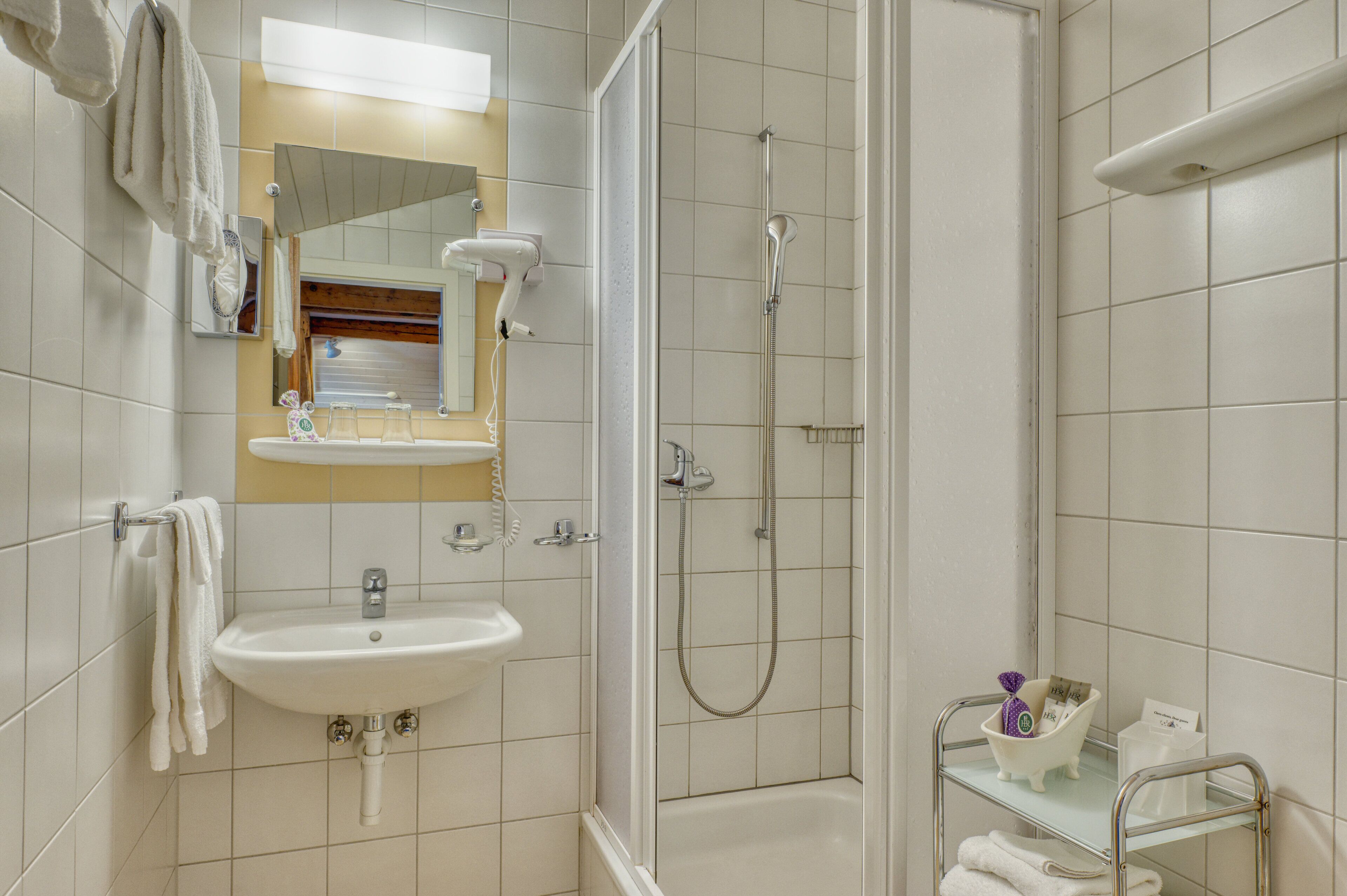 A bathroom with a sink, mirror, and shower.