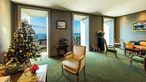 A living room with a Christmas tree, a view of the ocean, a dining area, and a large window. - Hôtel Bon Rivage (La Tour-de-Peilz)