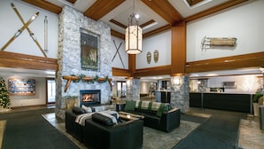 A spacious lobby with a stone fireplace, wooden beams, and a Christmas tree. - The Aspens by Whistler Premier (Whistler)