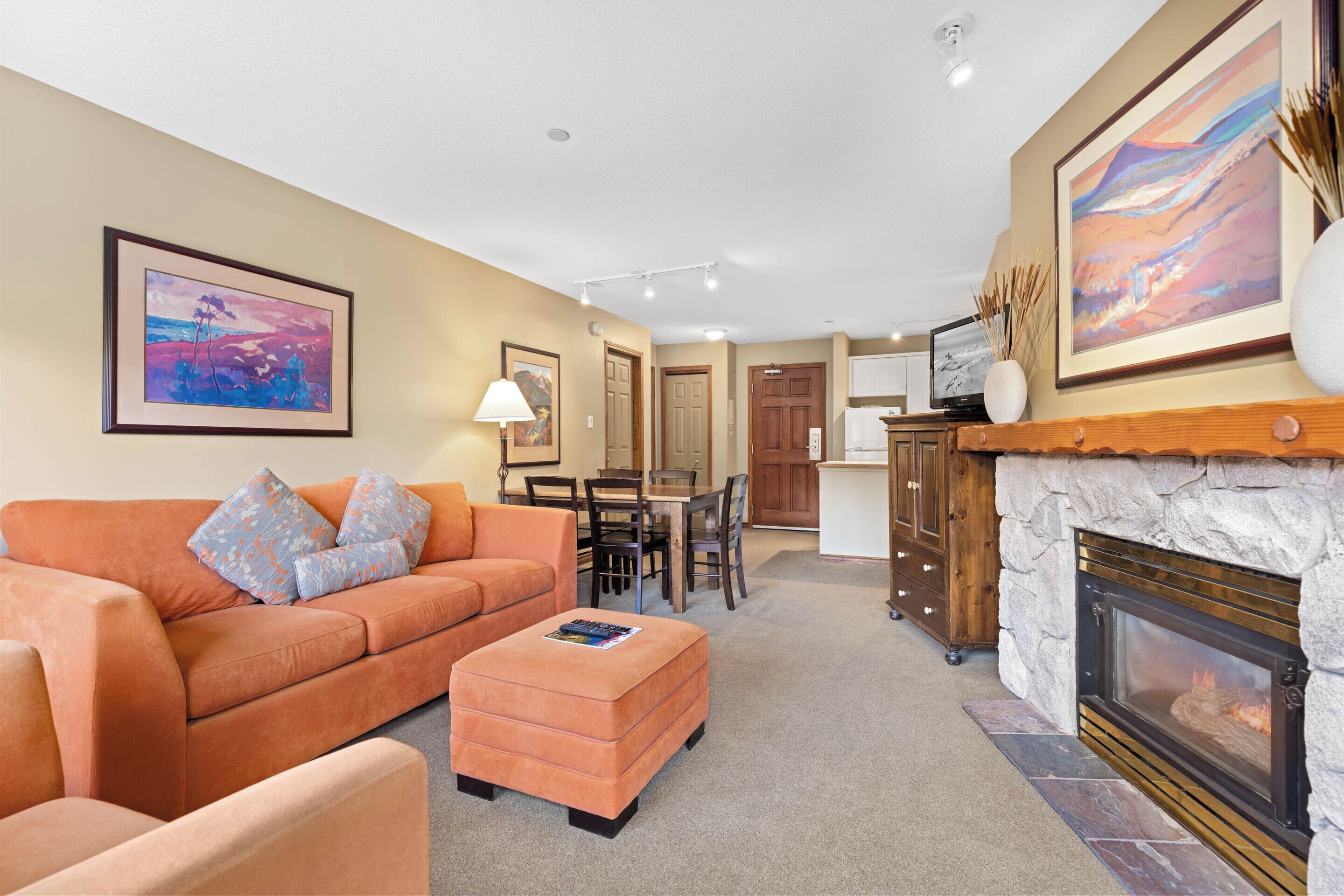 A living room with a fireplace, a sofa, and a dining area.