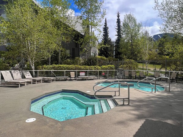 Un área de piscina con dos piscinas rectangulares, sillas de descanso y un muro de piedra.