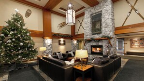A cozy lobby with a stone fireplace, leather sofas, a Christmas tree, and ski equipment on the wall. - The Aspens by Whistler Premier (Whistler)