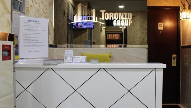 A hotel reception desk with a 'Toronto Group' sign, a fire extinguisher, and a 'Hotel Policy' notice. - Temple Street Hotel (Kowloon)