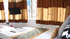 Une chambre d’hôtel avec un lit, un téléviseur fixé au mur et des rideaux.