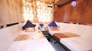 A room with two beds, each with a pillow and a small table in between. - Temple Street Hotel (Kowloon)