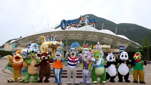 Un groupe de mascottes représentant des personnages de dessins animés se tient devant un bâtiment sur lequel on peut lire l’inscription « Ocean Park ».