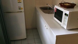 A compact kitchen with a refrigerator, a microwave, a sink, and a small countertop. - Evancourt Motel (Malvern East)