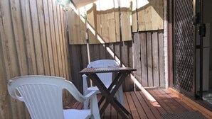 A patio with a wooden table and a white plastic chair. - Evancourt Motel (Malvern East)