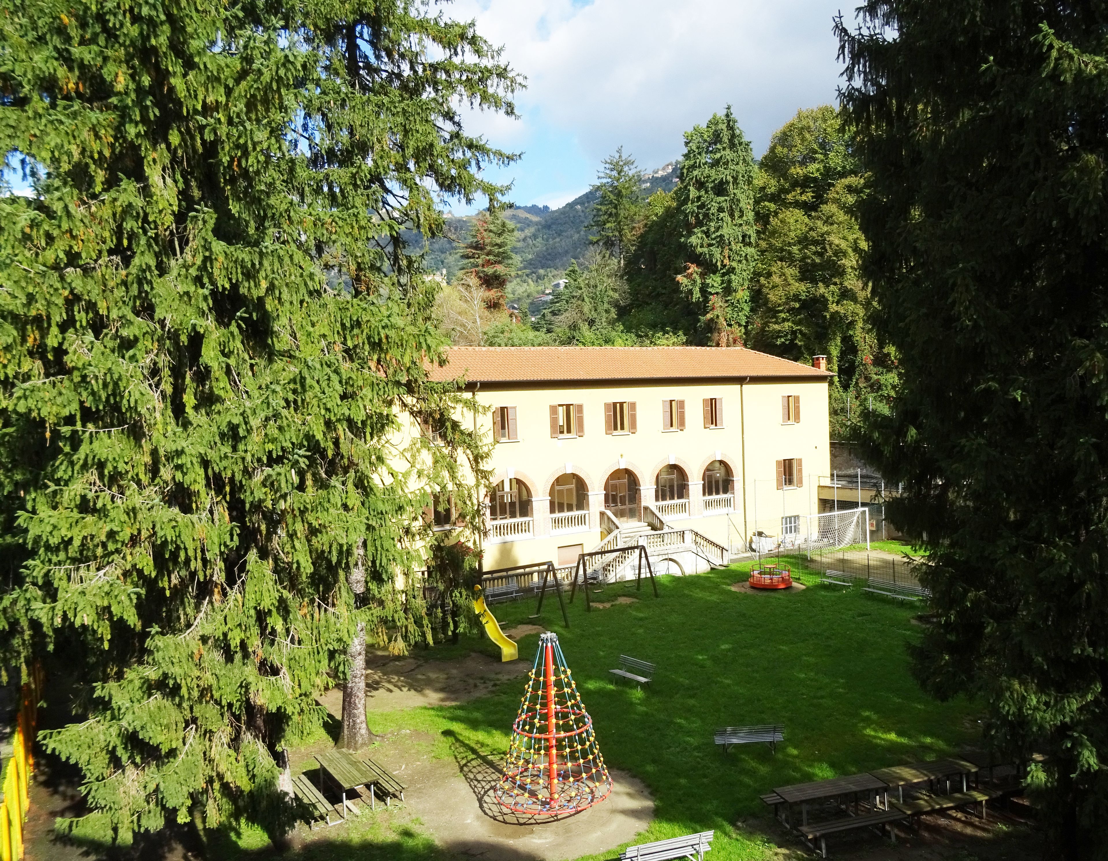A building with a courtyard, a playground, and a mountain backdrop.