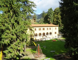 A building with a courtyard, a playground, and a mountain backdrop. - Victoria Hotels Carso (Como)