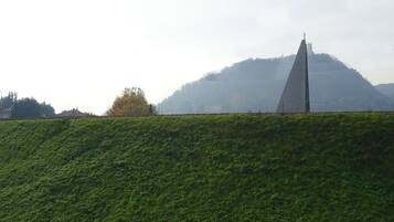 A grassy hill with a monument and a mountain in the background.