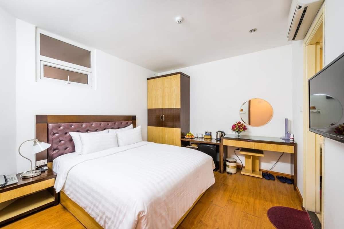 A hotel room with a bed, a desk, a TV, and a wardrobe.
