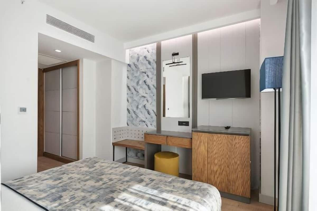 Une chambre d’hôtel moderne équipée d’un lit, d’un bureau, d’une télévision et d’une armoire.