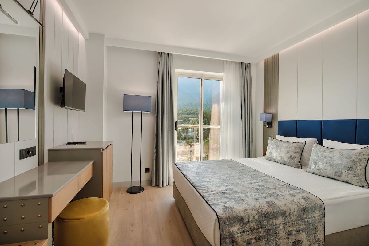 Une chambre d’hôtel moderne dotée d’un grand lit, d’un bureau, d’une télévision à écran plat et offrant une vue sur l’extérieur.