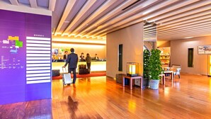A hotel lobby with wooden flooring, a reception desk, a Christmas tree, and a wall with a map and text. - Sansuien (Kochi)