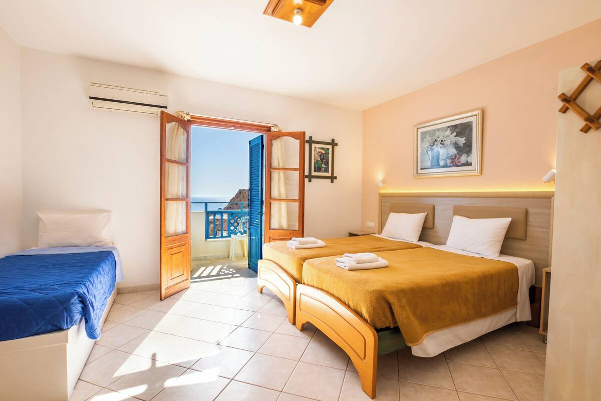 A hotel room with two beds, a balcony, and a painting on the wall.