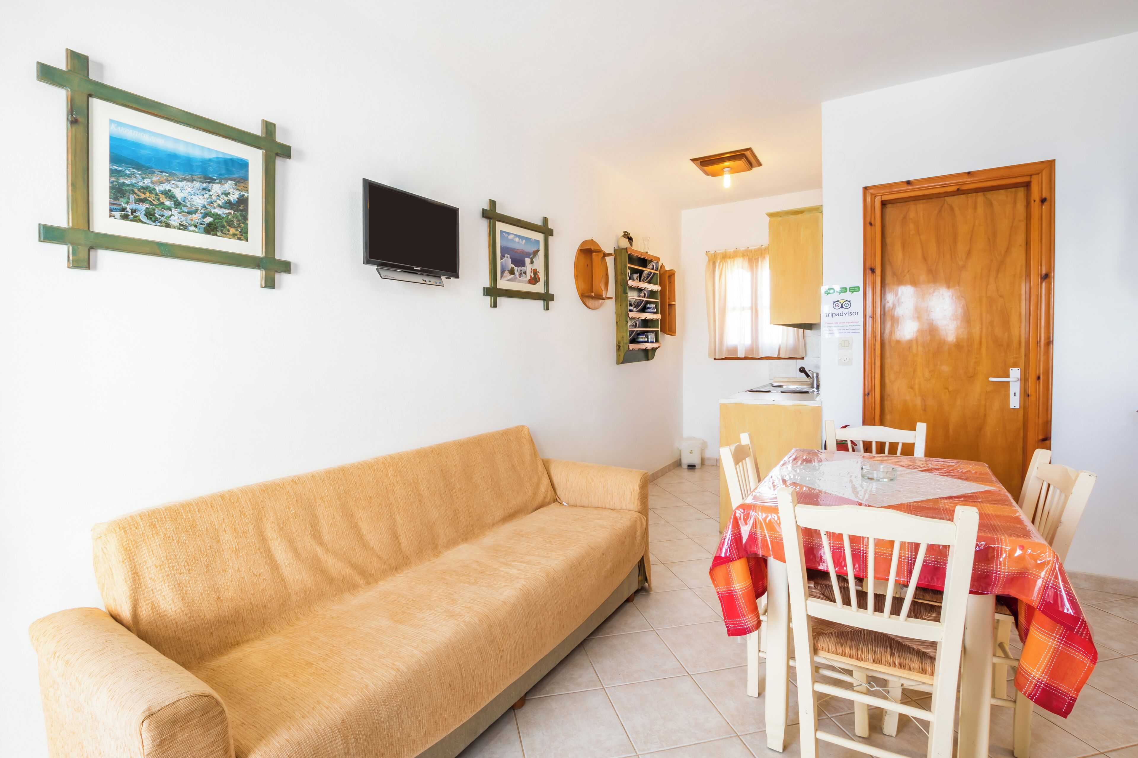 Un salon avec un canapé, une table à manger et des chaises, un téléviseur et une porte en bois.