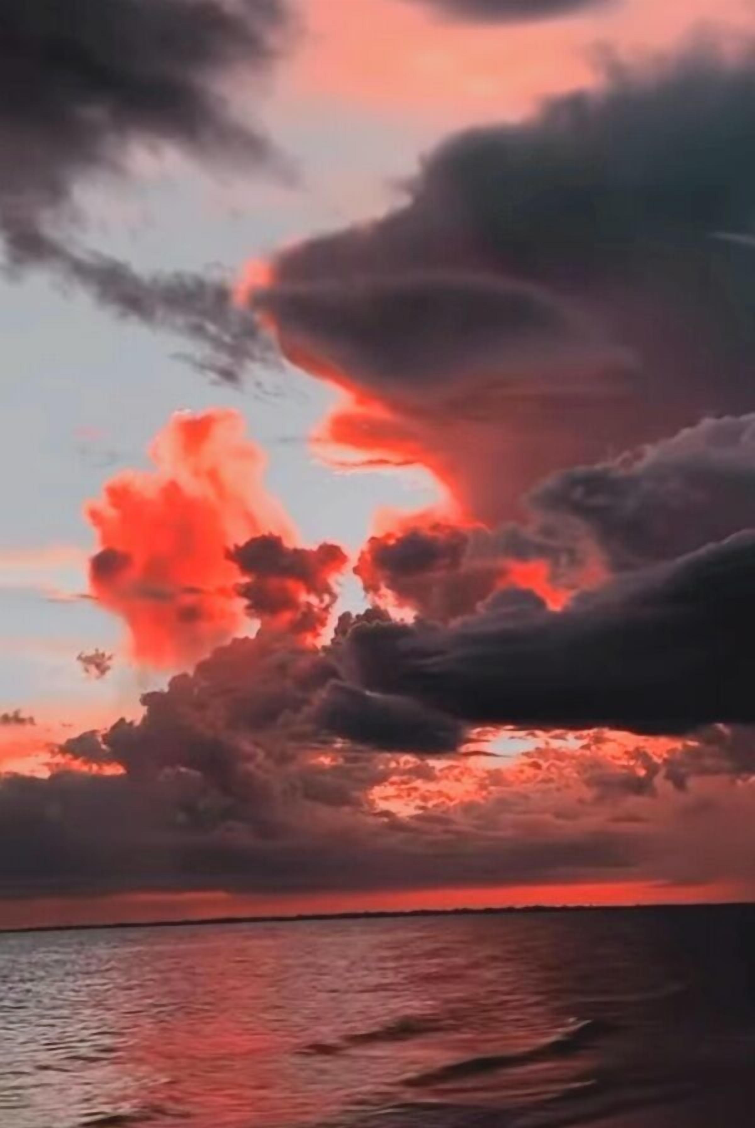A sunset over a body of water with clouds reflecting the sky's colors.