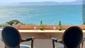 Een tafel met twee stoelen gericht op een schilderachtig uitzicht over zee en bergen.