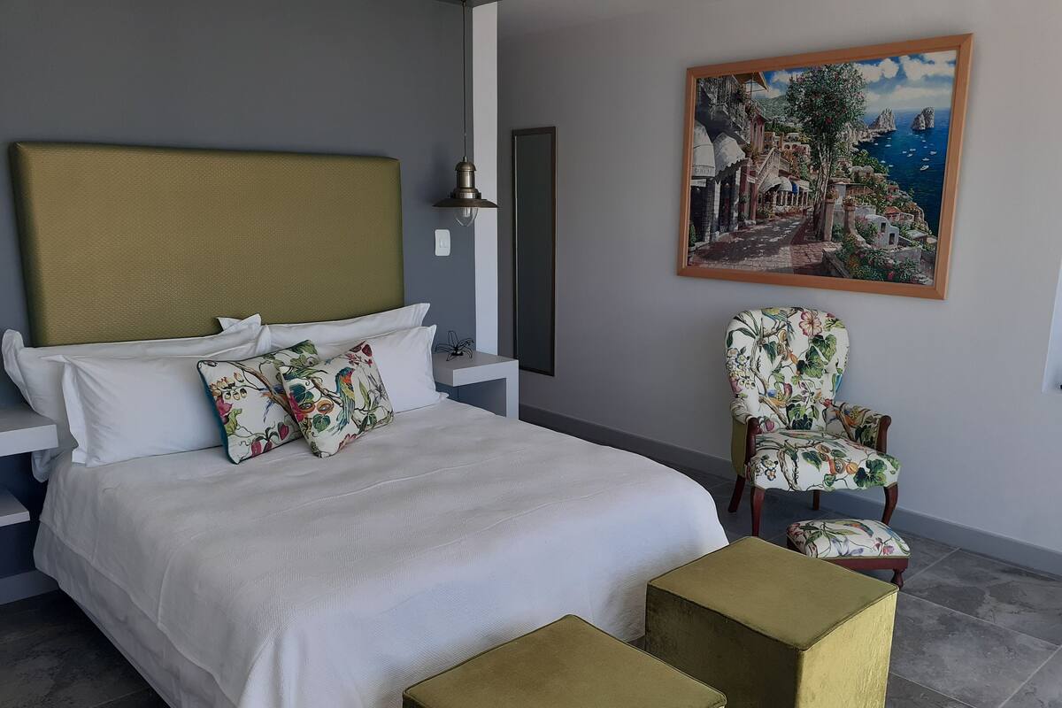 A bedroom with a bed, a chair, and a painting on the wall.