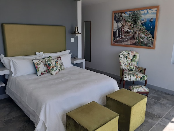 Un dormitorio con una cama, una silla y un cuadro en la pared.