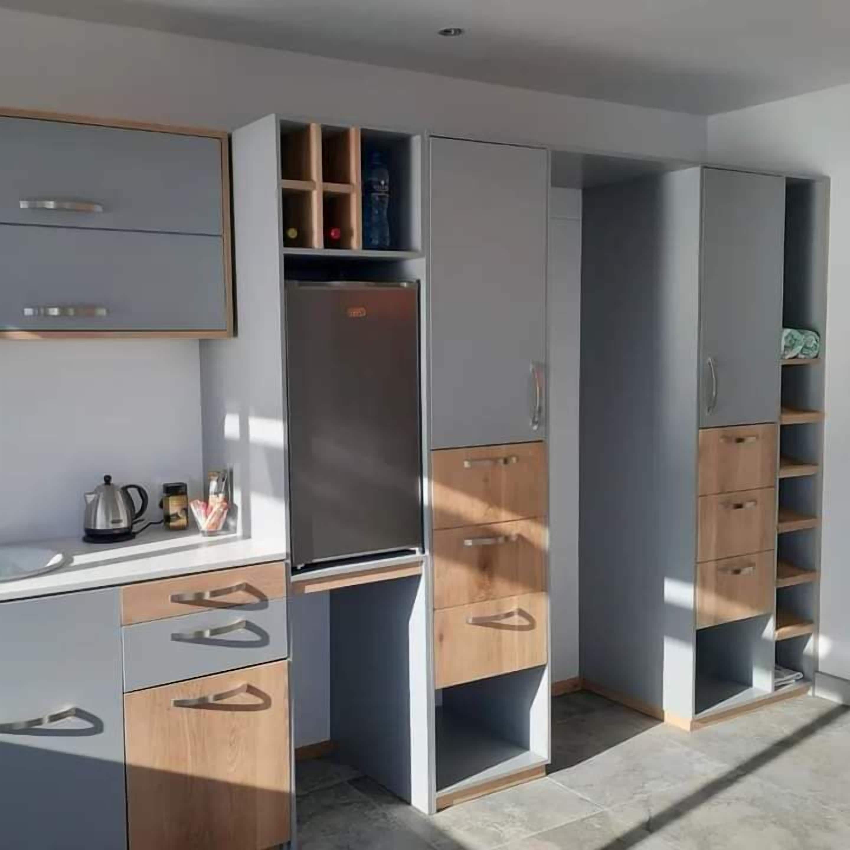A modern kitchen with grey cabinets, wooden drawers, and a built-in oven.